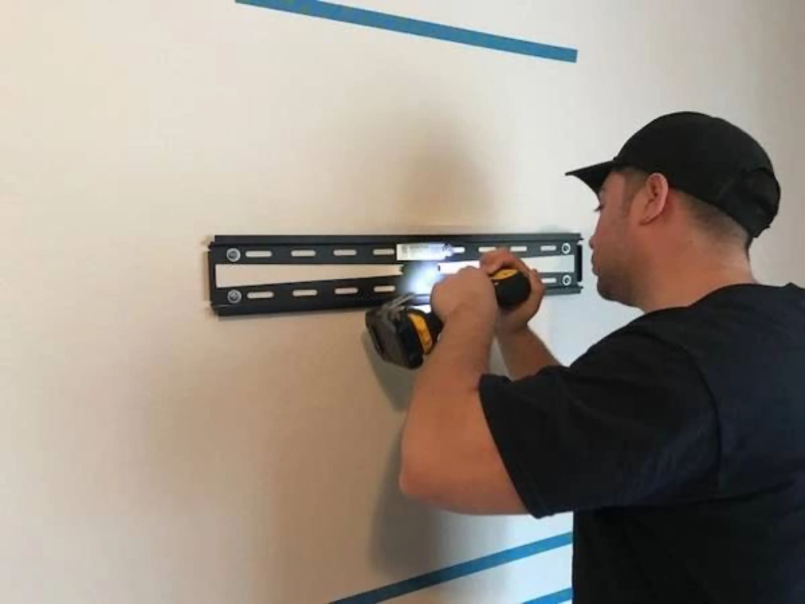 Mountzilla installer leveling a TV bracket on drywall